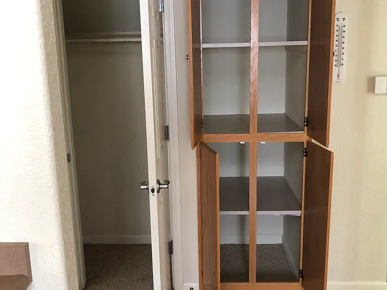 Coat closet and extra storage cabinets in hallway. Kitchen view.
