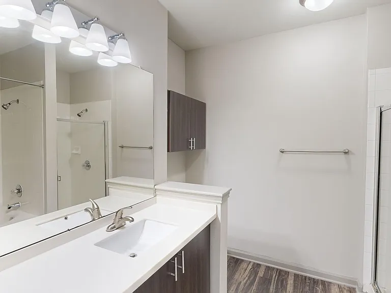Apartment bathroom with large soaking tub and wood-style flooring.