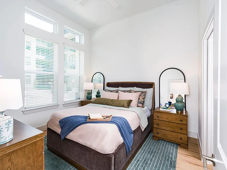 Primary bedroom with tall windows, and warm wood flooring, creating a bright and comfortable retreat.