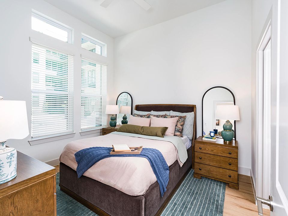 Primary bedroom with tall windows, and warm wood flooring, creating a bright and comfortable retreat.