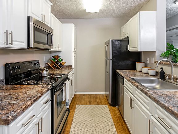 Enjoy cooking in a fully equipped kitchen with sleek stainless appliances, granite-inspired counters, and bright white cabinetry for a clean, modern look.