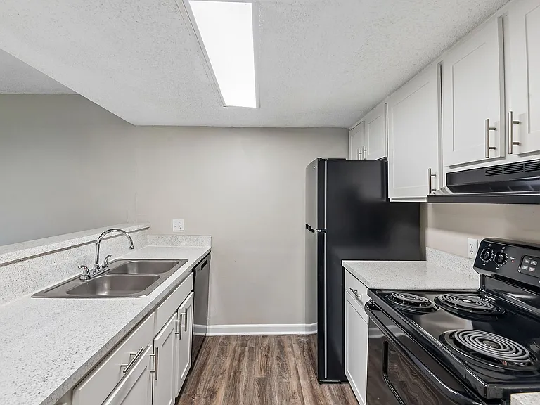 Modern kitchen with sleek appliances, white cabinetry, and stylish countertops, enhanced by natural light from the ceiling skylight.
