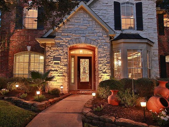 The landscape lighting is beautiful on this home and the Austin stone is a stunning touch of elegance. Herringbone brick detail on the arched windows with shutter accents.