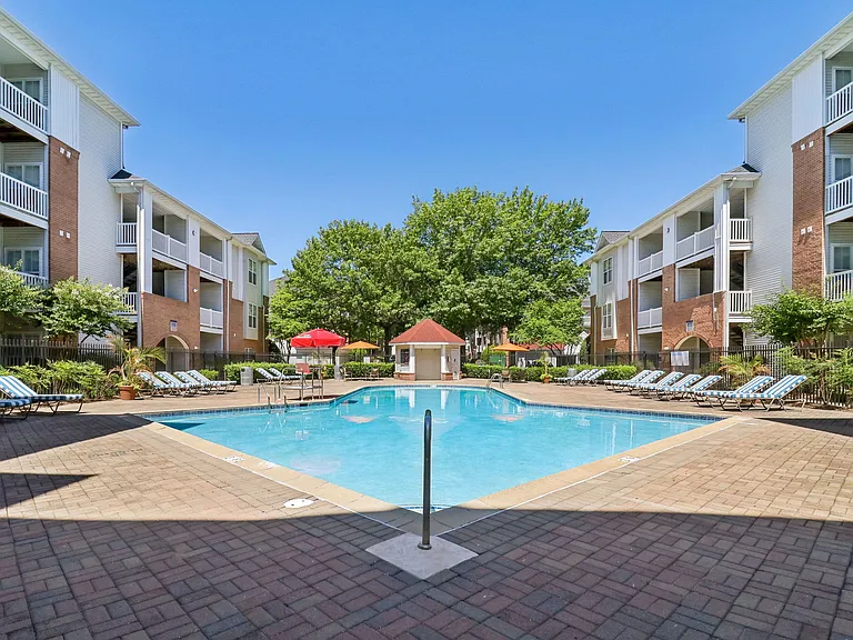 Serene swimming pool with lounge seating, patio tables, and umbrellas