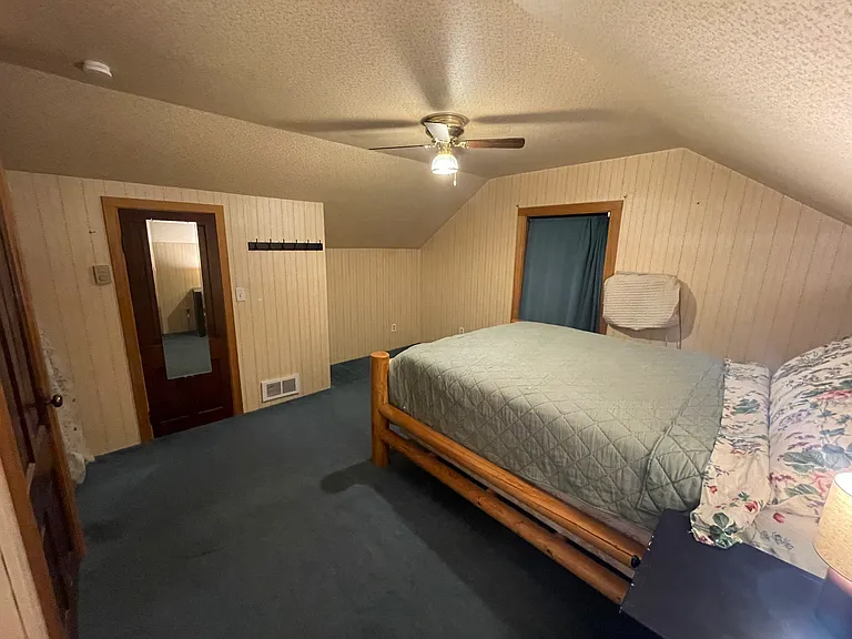 Wall mounted AC unit by window, thermostat controlled heating in bedroom.