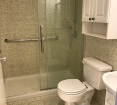 Bathroom with tiles with glass shower doors and a large vanity sink.