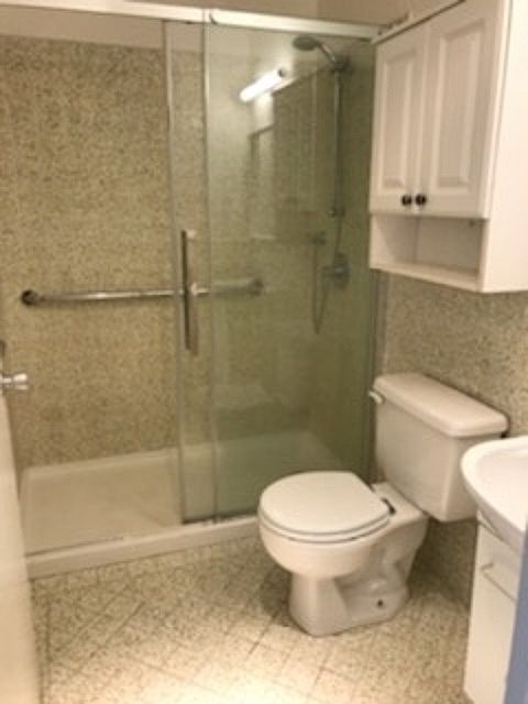Bathroom with tiles with glass shower doors and a large vanity sink.