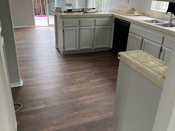 View of beautiful 9" by 72" commercial grade LVP flooring.redwood deck in the distance. Mops now replaced with brand new inviting cushioned patio conversation sets. Fence has new paint. ample area for attractive breakfast dining set if wanted between the