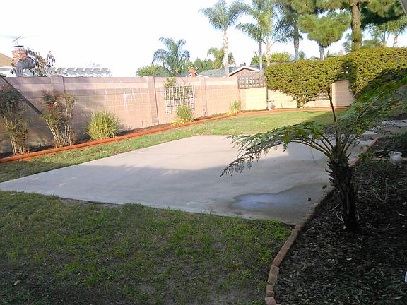 Large fenced block walls backyard with a patio area perfect