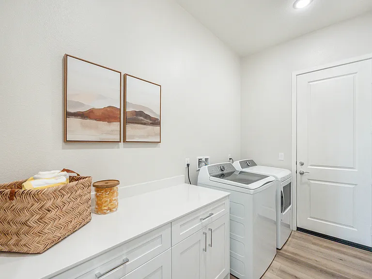 The laundry room features a matching washer and dryer, laundry pods, iron, and ironing board to meet your needs.