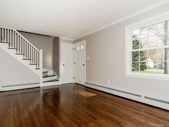 Living room with new windows, refinished hardwood floors and freshly painted interior. Note the baseboard heating.