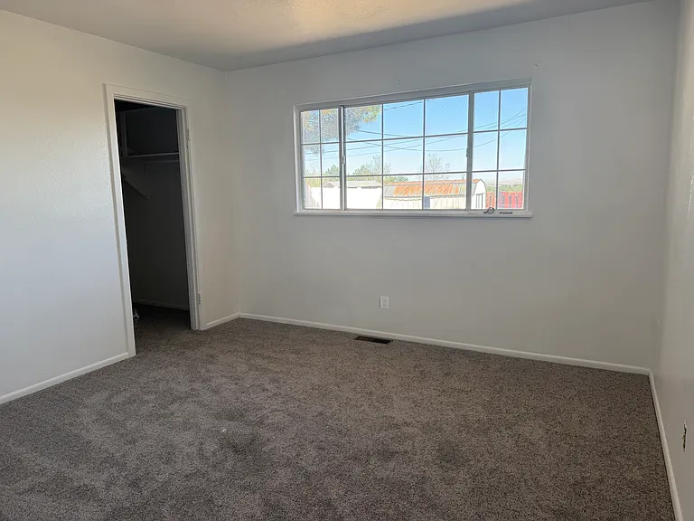Bedroom 2 features a large picture window that fills the room with natural light, a spacious walk-in closet, updated carpeting, modern light fixtures, and upgraded electrical outlets, creating a comfortable and inviting retreat.