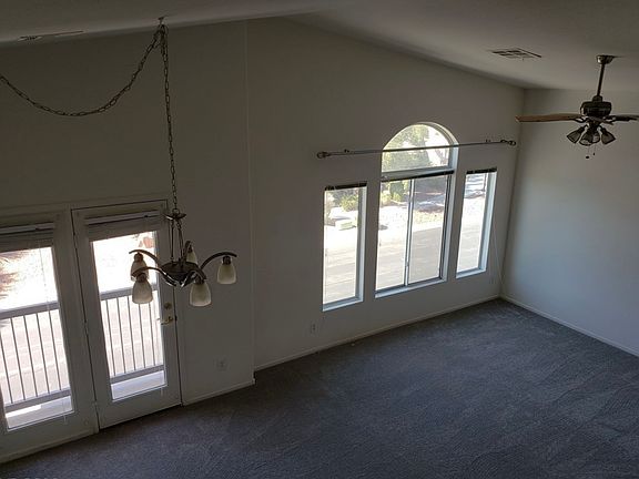 Spacious living room and dining room with high ceilings and balcony. Note: living room has a ceiling fan and updated lighting fixtures not depicted in photos.