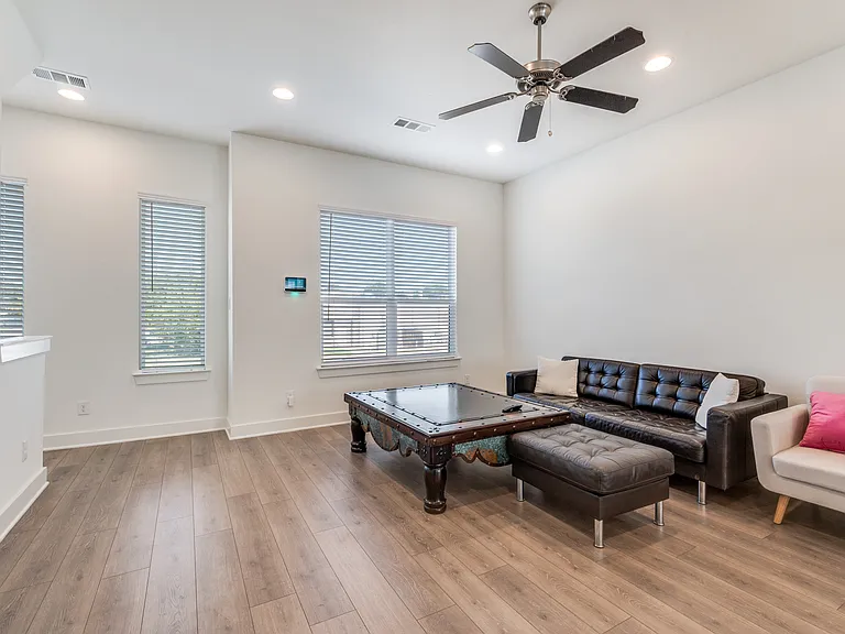 Living room (comes unfurnished) with ceiling fan and lots of natural light.