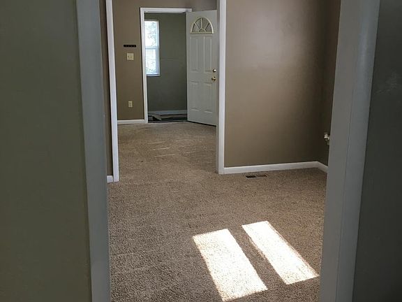 Kitchen view of dining room, living room, and front porch en