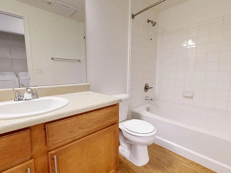 Apartment bathroom with soaking tub and large mirror.