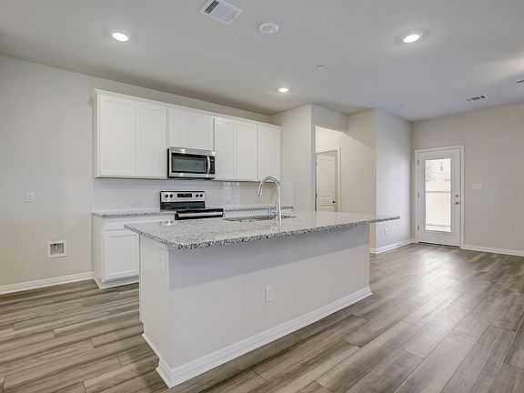 The kitchen features linen-colored cabinets and granite countertops.