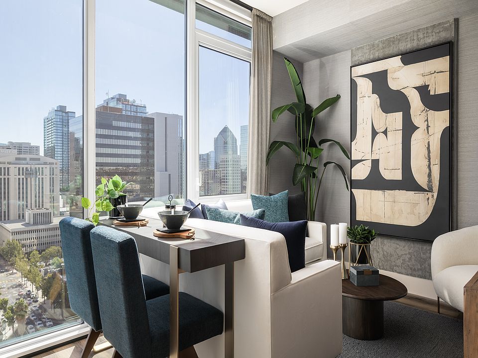 Modern apartment interior with elegant dining area, plush seating, and panoramic city views through large windows.