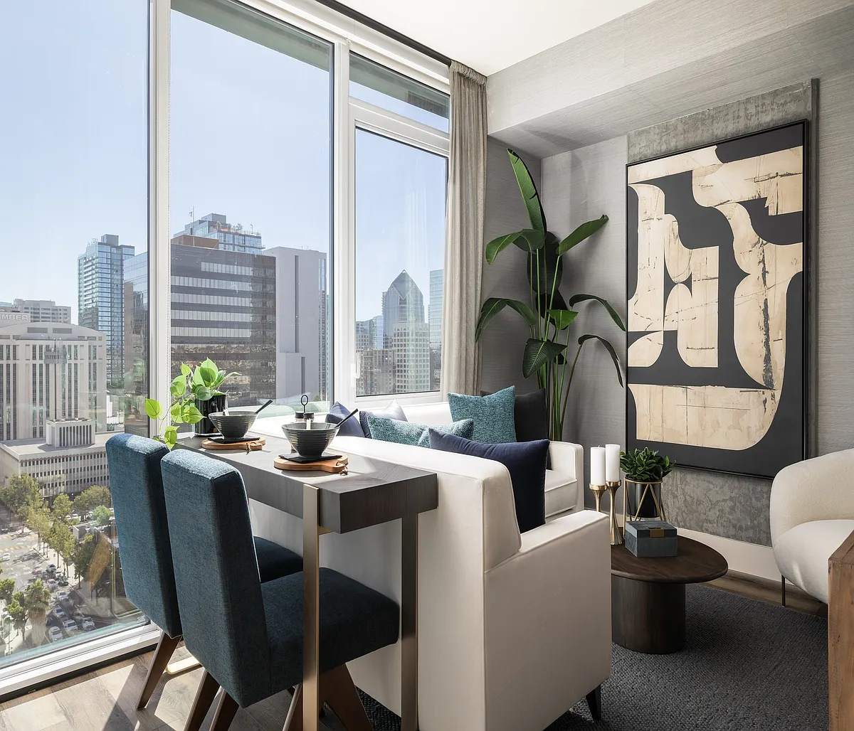 Modern apartment interior with elegant dining area, plush seating, and panoramic city views through large windows. - Ancora