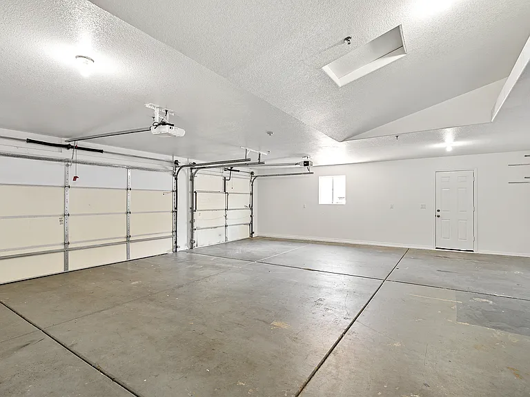 Looking into garage from house entrance. Across the garage is a side entrance from the Back house driveway (left side of the Front house).