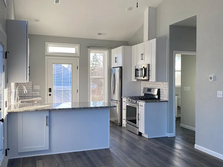 Open concept living area and kitchen with peninsula countertop and recessed lighting.