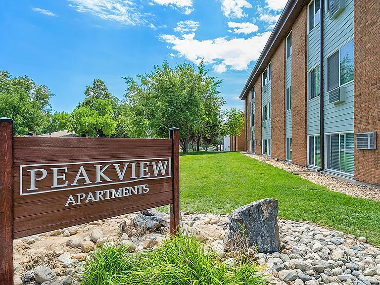 Inviting exterior view of Peakview Apartments, showcasing beautiful landscaping and clear blue skies.