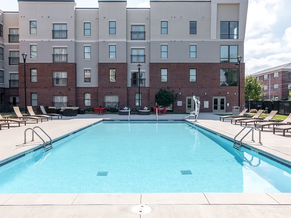 Resort-style swimming pool surrounded by lounge chairs at The Pad apartment community.