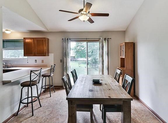Dining area with ceiling fan open to kitchen and breakfast bar