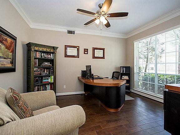 The spacious office has a window to the front yard, wood flooring and a ceiling fan.