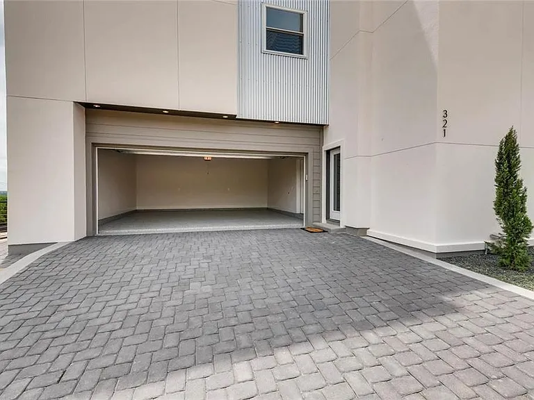 Leading to an extra-large two-car garage with a finished concrete floor, complemented by a paver driveway and equipped with an EV charger.