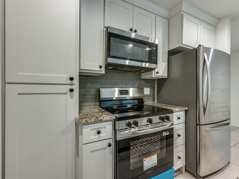Modern kitchen featuring white shaker cabinetry, stainless steel appliances, granite-style countertops, and a gray subway tile backsplash
