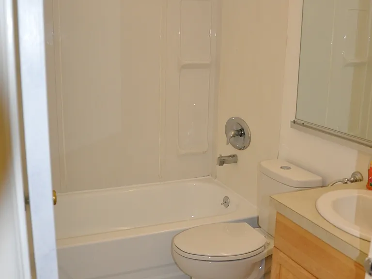 Full bathroom with new flooring accessible through the hallway.