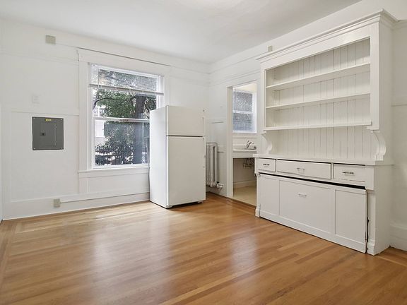 Kitchen features refrigerator, a sink, and a window, floor is made of wood