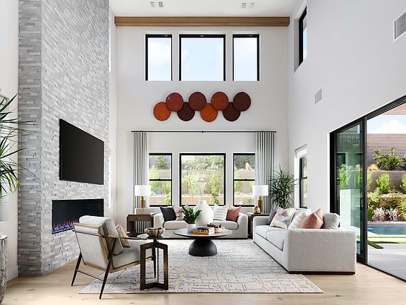 A spacious and modern living room with large windows, a fireplace, and a cozy seating arrangement fe