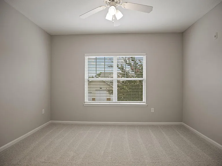 A room with a ceiling fan and a window with blinds.