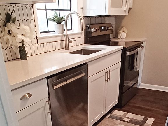 Nice Galley Kitchen with marble countertops, white wood cabinets, and newer appliances - Flat top Range, Dishwasher, Microwave, and Refrigerator.