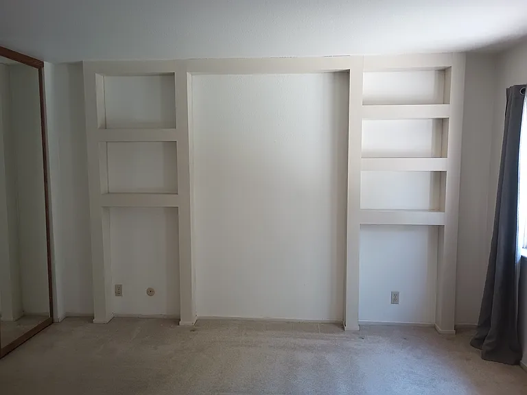 Master bedroom with built-in shelving, ceiling fan and his and her closets