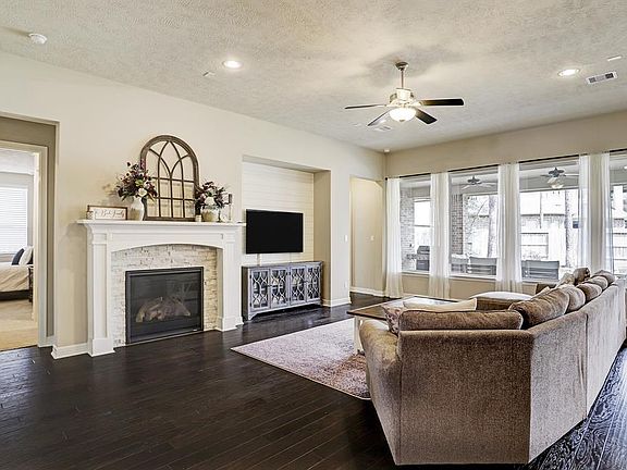 Spacious family room with beautiful wood floors. Large windows looking out to covered patio. Fireplace with upgraded detailing and remote on/off. Also features shiplap wall behind TV. Plenty of natural light!