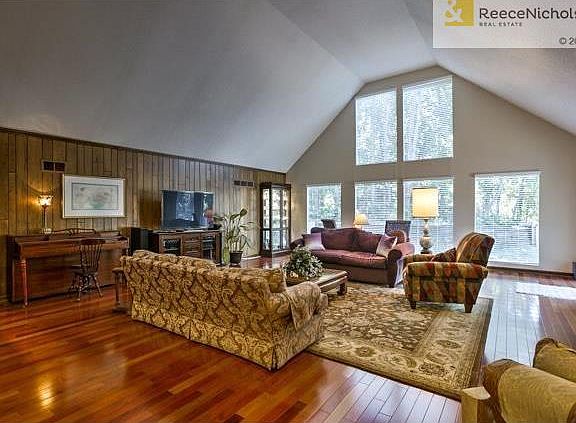Large great room with vaulted ceilings overlooking the treed backyard. The kitchen and dining rooms are to the right, while access to the bedrooms is to the left.