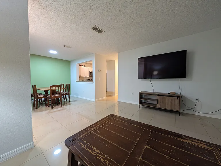 Living room with dining room, kitchen opening and hallway in view