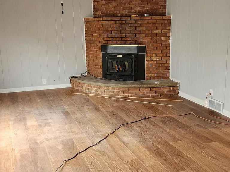 The den, new vinyl flooring. wood fireplace. Because of insurance, the fireplace is just for looks. it can't be used. sorry. lots of light