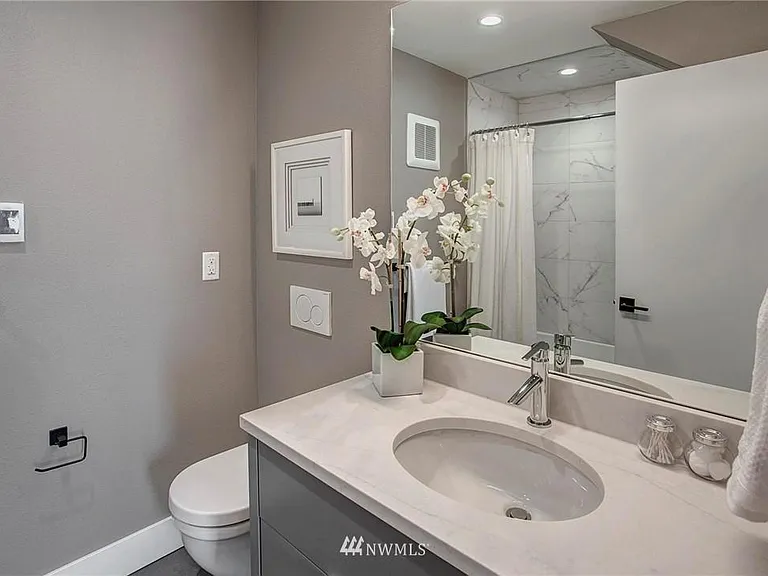 First-floor spa-style full bath with marble vanity and wall, plus radiant heated floors for added comfort.
