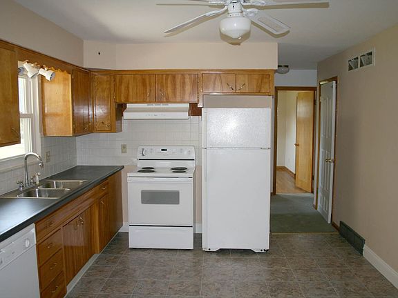 Spacious kitchen comes equipped with new white appliances, neutral flooring an
