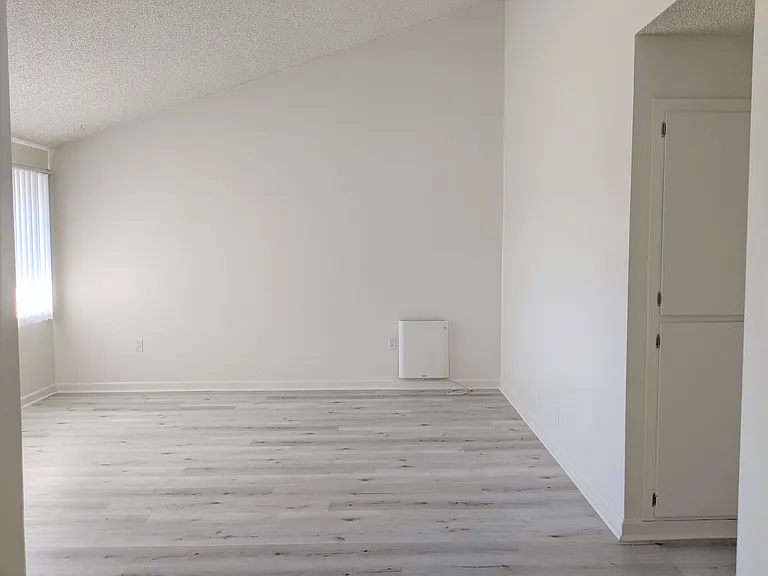 View of living room and hallway to bedrooms showing easy care wood style flooring at the Steckel Apartments in Santa Paula, California.