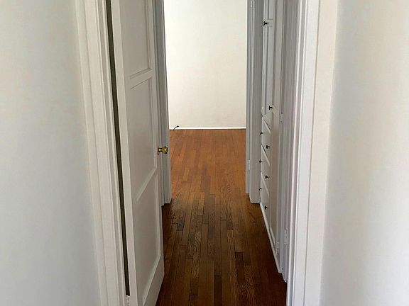 Long hallway leading to bedroom with built-in linen closet 