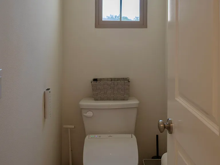 Primary Bathroom: Inside the private toilet room, featuring a window positioned above the toilet to provide natural light and ventilation.