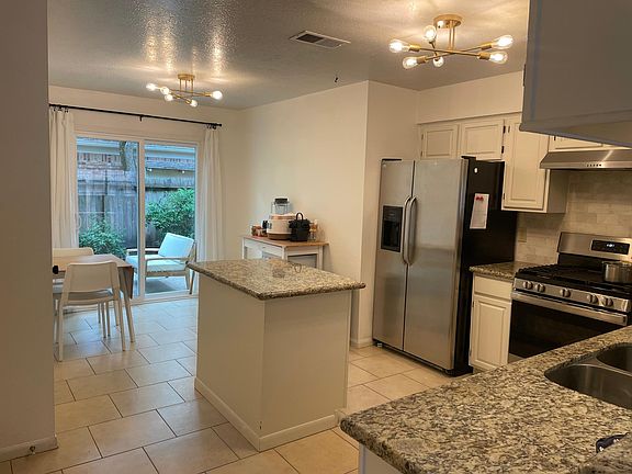Kitchen with moveable island, stainless steel appliances, and granite countertops.