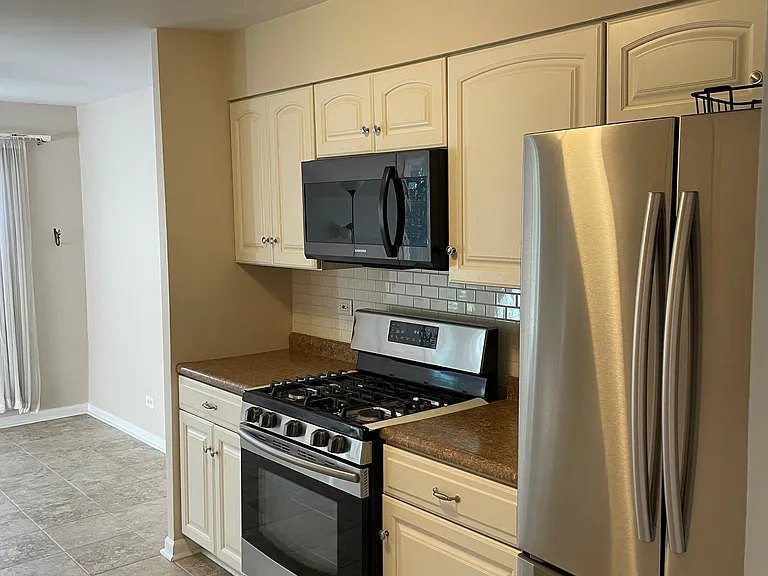 kitchen with stainless steel Samsung stove, over the range microwave, and fridge with bottom shelf freezer w/ ice maker