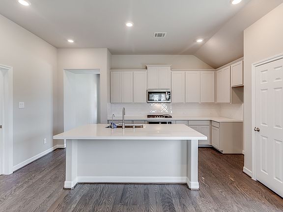 This spacious kitchen features white stained wood cabinets, quartz countertops, SS appliances, tile