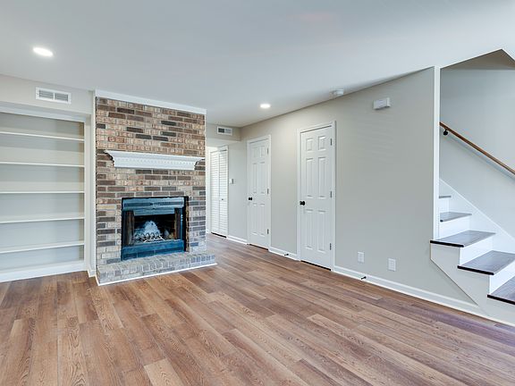 Living room with hardwood floors throughout, a wood burning fireplace, and built in bookshelf.